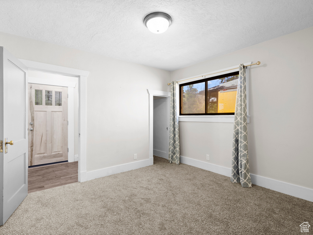 Unfurnished bedroom featuring carpet, a textured ceiling, and baseboards