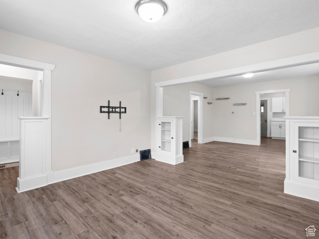 Unfurnished living room featuring wood finished floors and baseboards