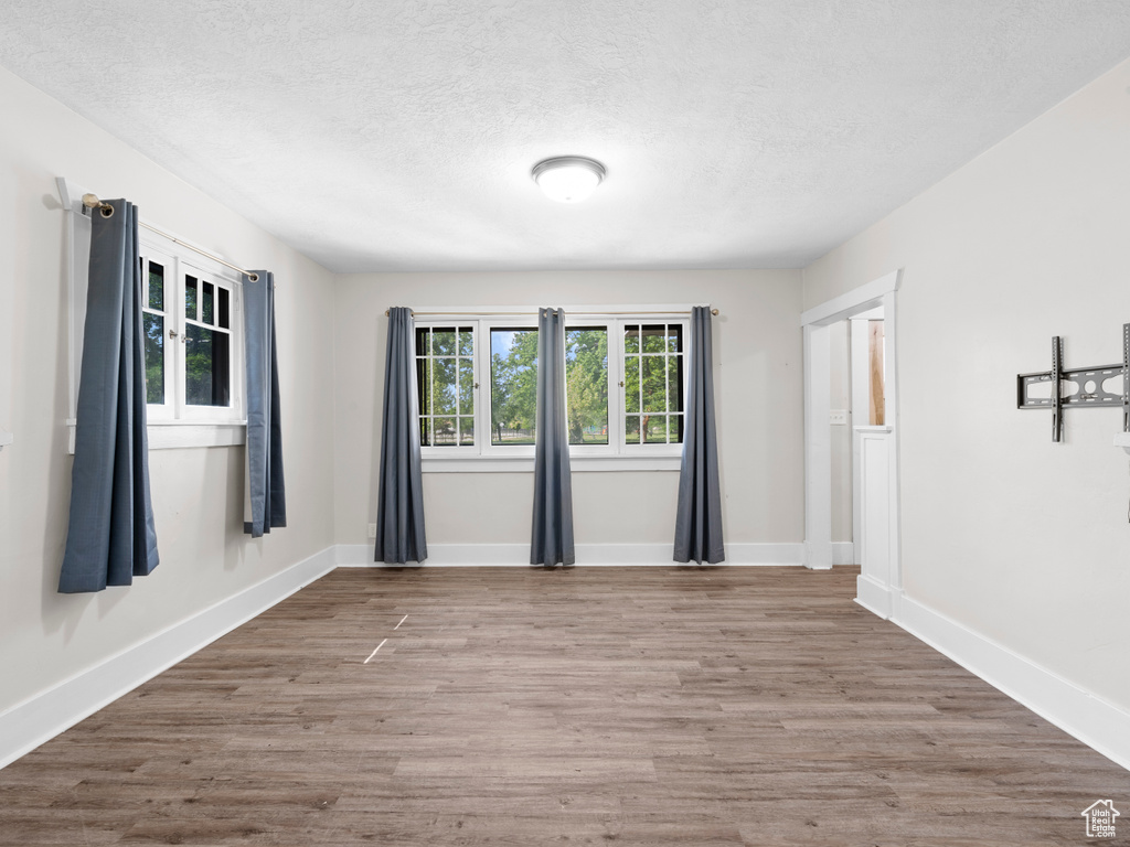 Unfurnished room featuring a textured ceiling, wood finished floors, and baseboards