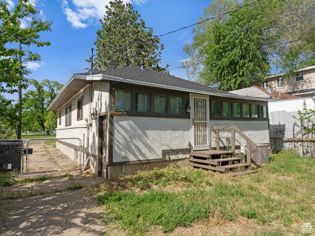 View of front of house with roof with shingles, entry steps, and a gate