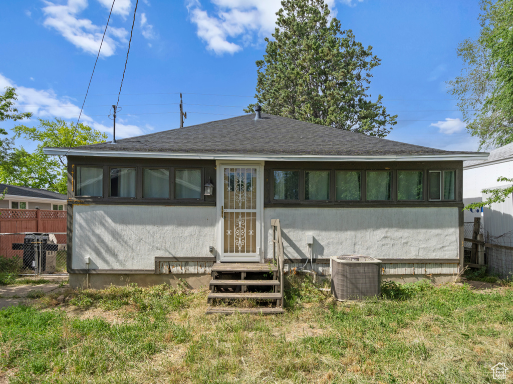 Rear view of property featuring central air condition unit, a shingled roof, and stucco siding
