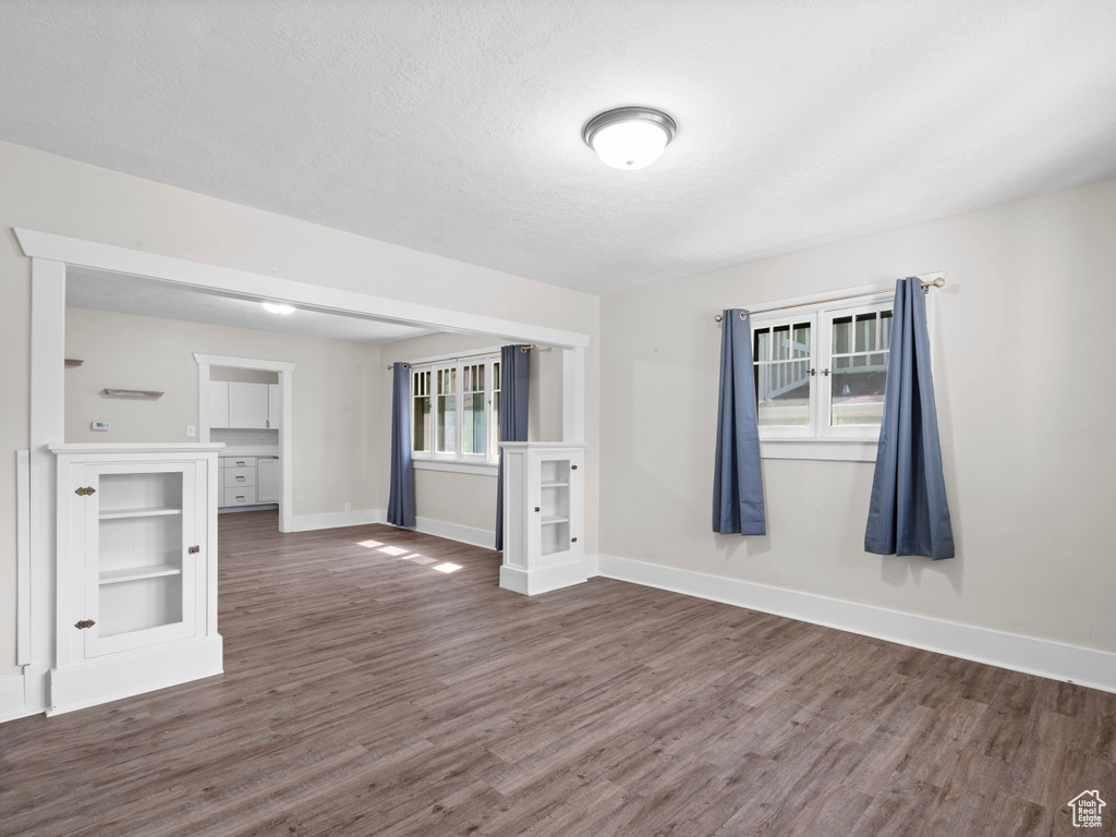 Empty room featuring wood finished floors, baseboards, and a textured ceiling