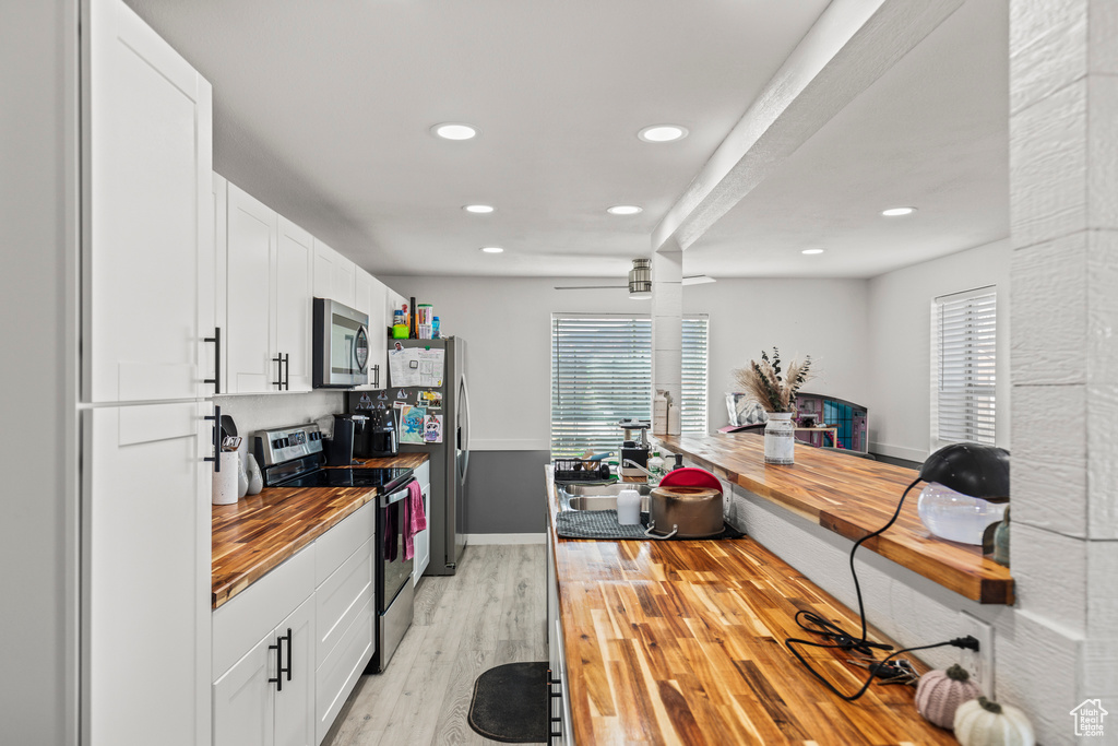 Kitchen with stainless steel appliances, butcher block counters, light wood-type flooring, plenty of natural light, and recessed lighting