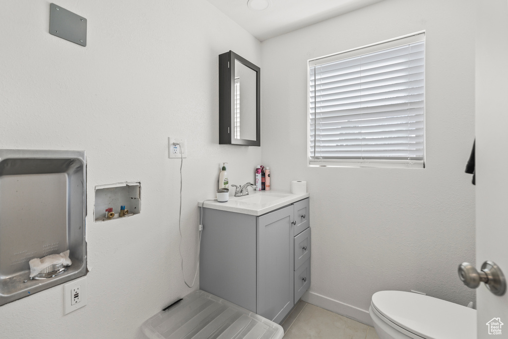 Half bath with vanity, toilet, tile patterned flooring, and baseboards