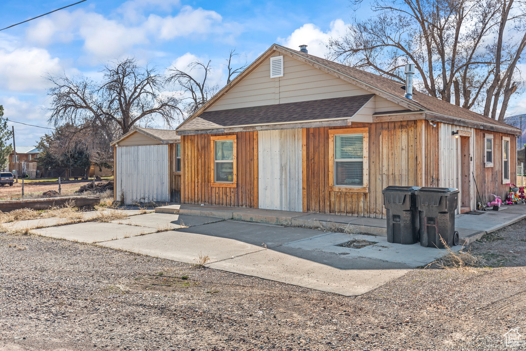 View of front of house with roof with shingles and an outbuilding