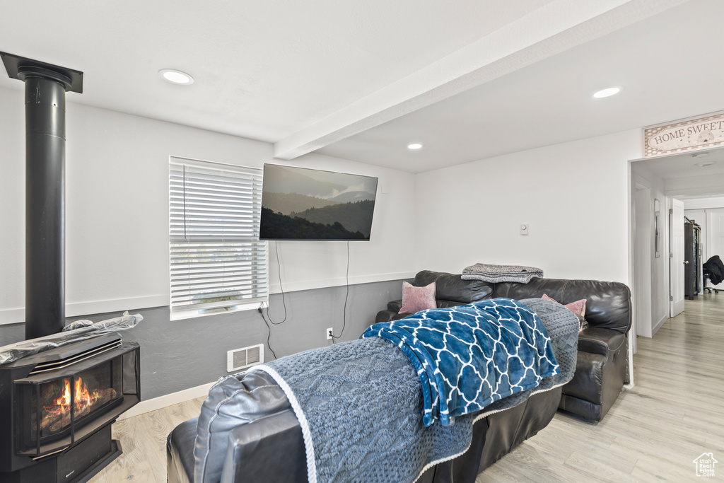 Living area featuring a wood stove, wood finished floors, beam ceiling, recessed lighting, and baseboards