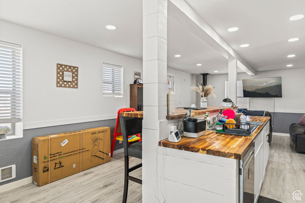 Kitchen with light wood finished floors, ornate columns, wood counters, recessed lighting, and baseboards