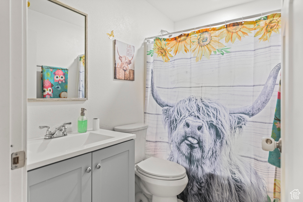 Bathroom with toilet, vanity, and curtained shower