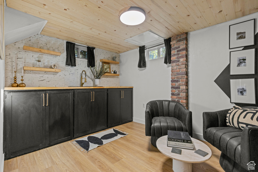 Bar area with a sink, wooden ceiling, and light wood-type flooring
