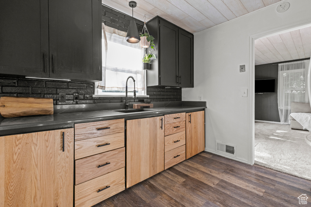 Kitchen featuring a sink, dark countertops, tasteful backsplash, wooden ceiling, and dark wood-type flooring