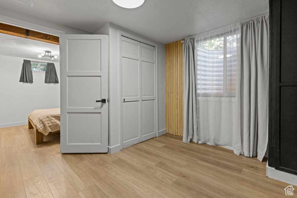 Unfurnished bedroom with light wood finished floors, baseboards, a closet, and a chandelier