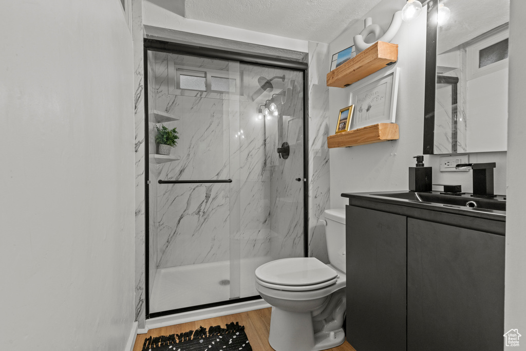 Full bathroom featuring toilet, vanity, a marble finish shower, and wood finished floors
