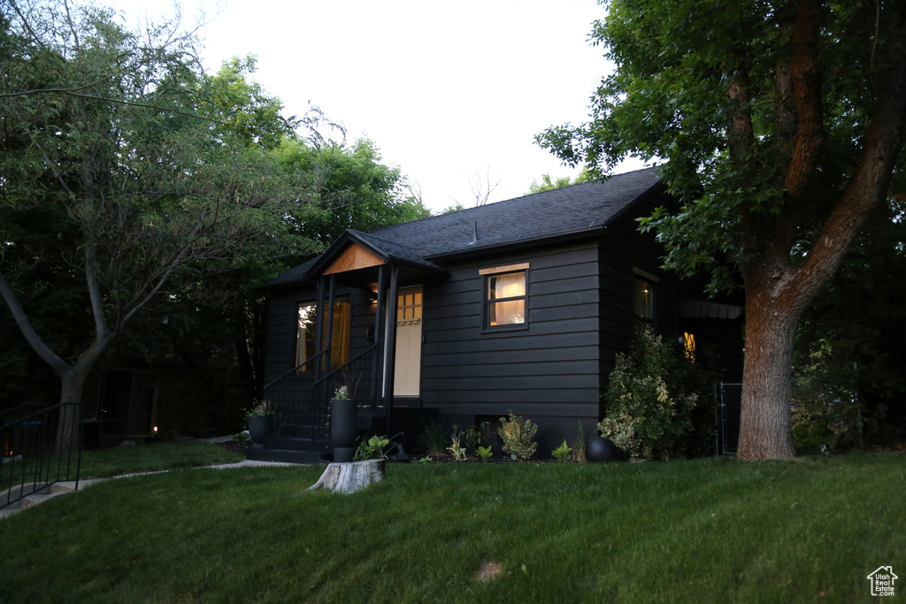 View of front of home featuring a front yard and roof with shingles
