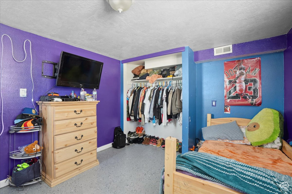 Bedroom with a closet, baseboards, a textured ceiling, and speckled floor