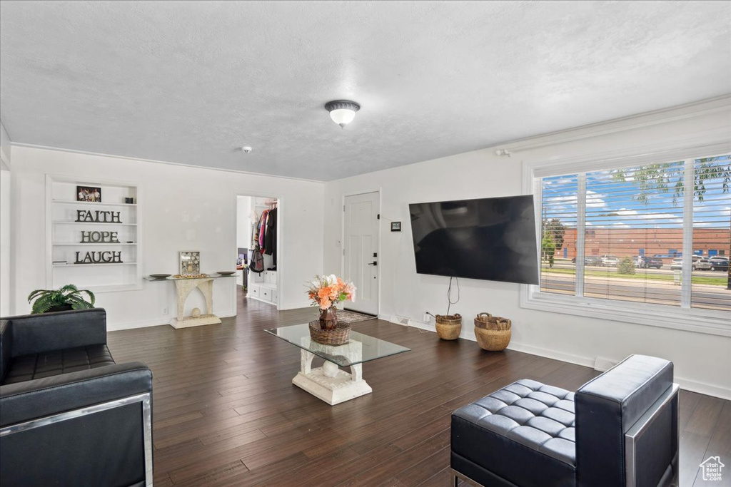 Living room with baseboards, built in features, wood finished floors, and a textured ceiling