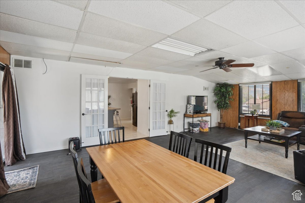 Dining area with french doors, wood finished floors, a drop ceiling, ceiling fan, and baseboards