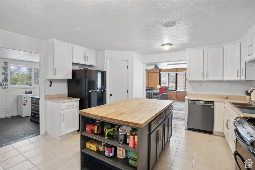 Kitchen featuring stainless steel appliances, white cabinets, butcher block counters, open shelves, and light tile patterned floors