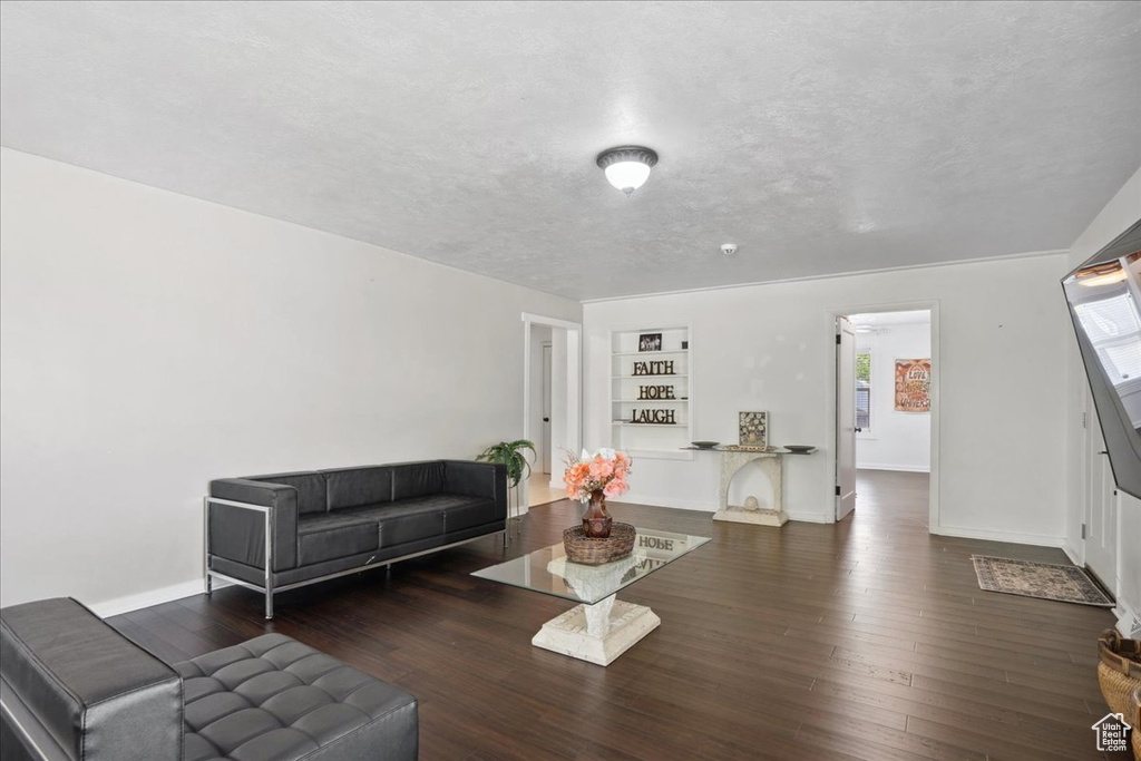 Living room with hardwood / wood-style floors, baseboards, built in shelves, and a textured ceiling