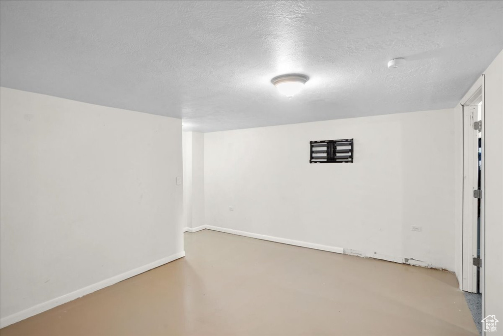 Finished basement with a textured ceiling and baseboards