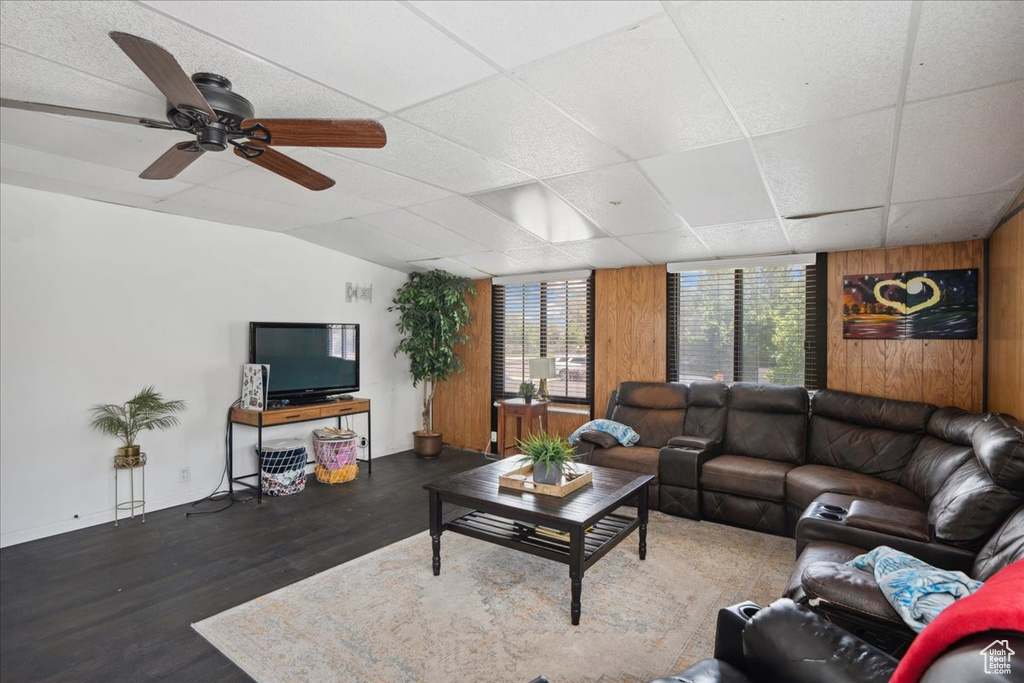 Living room featuring wood finished floors, wooden walls, lofted ceiling, and a ceiling fan