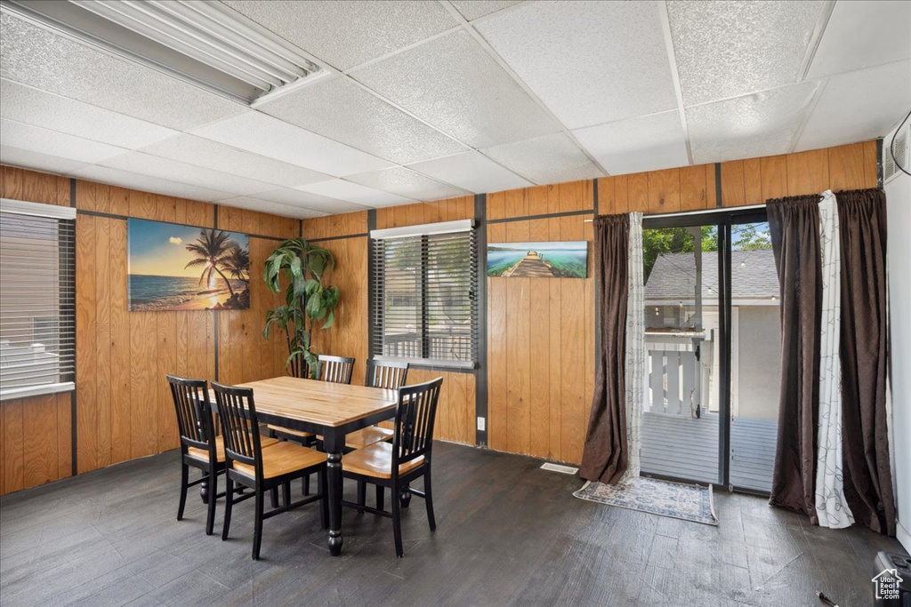 Dining area featuring wood walls, a drop ceiling, and dark wood-style floors