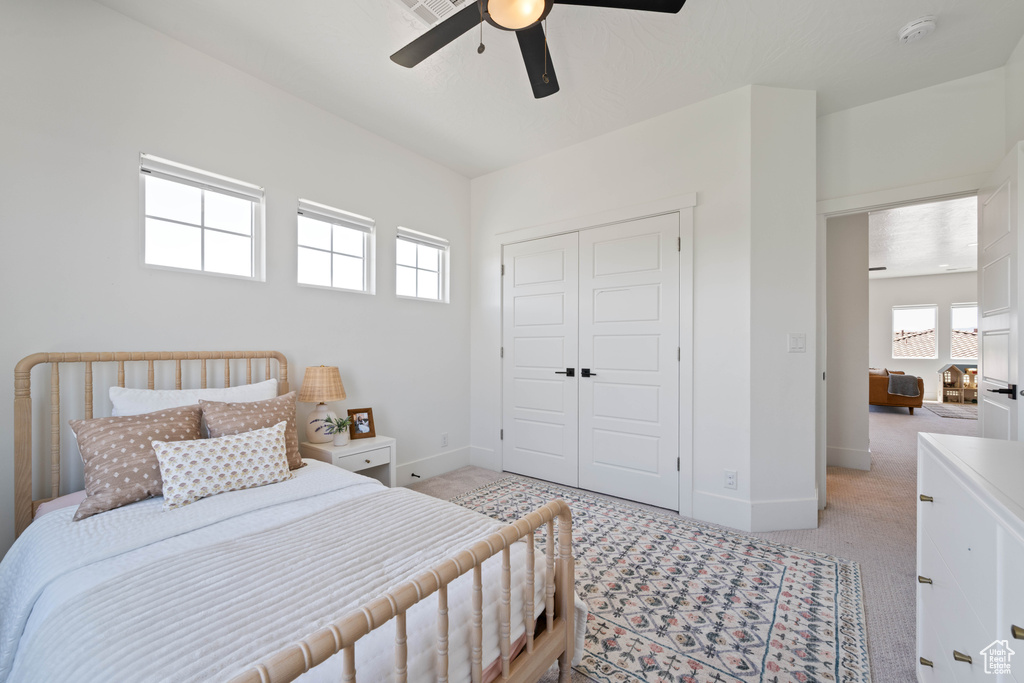 Bedroom featuring light carpet, multiple windows, and a closet