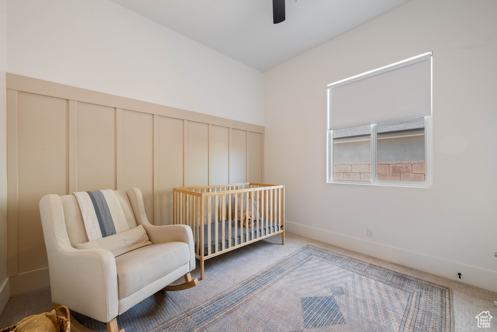 Bedroom with carpet floors, a decorative wall, ceiling fan, and a nursery area