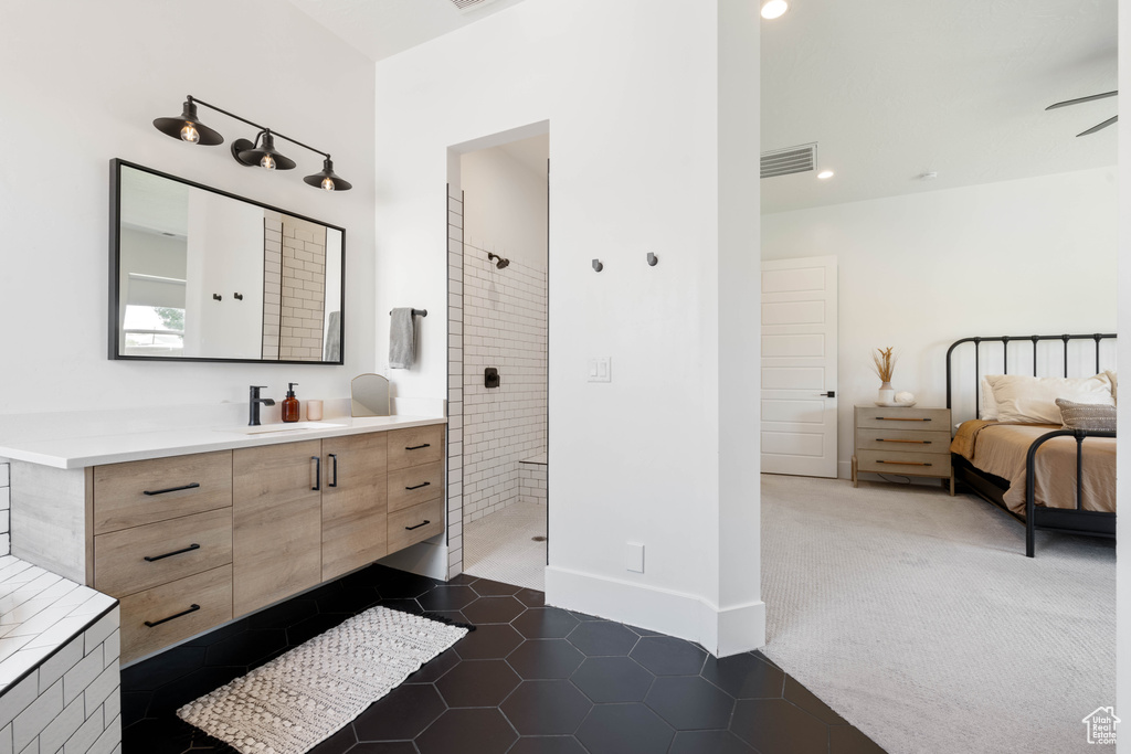 Ensuite bathroom featuring vanity, tiled shower, tile patterned flooring, baseboards, and recessed lighting