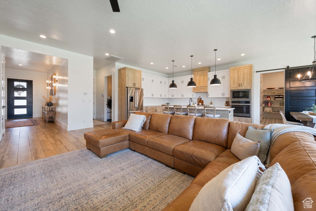 Living area featuring baseboards, a chandelier, recessed lighting, and light wood finished floors