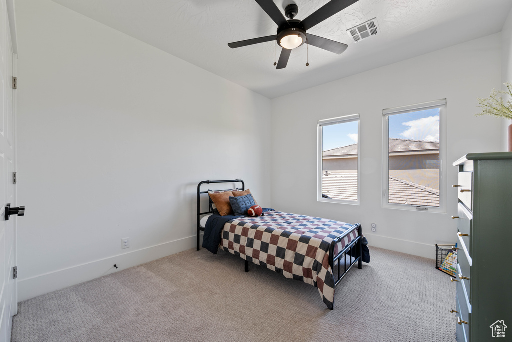 Bedroom featuring light colored carpet, baseboards, and a ceiling fan
