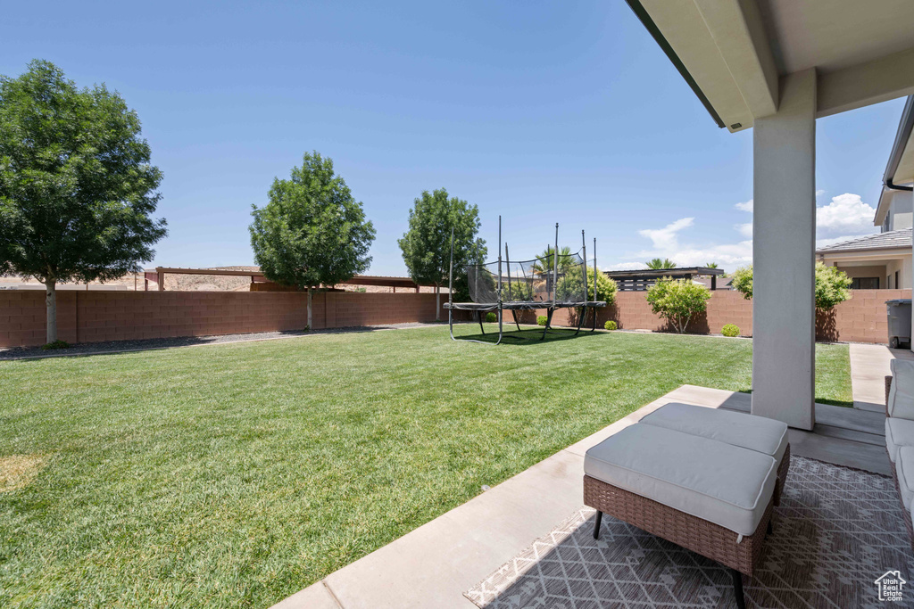 View of yard featuring a trampoline and a patio area