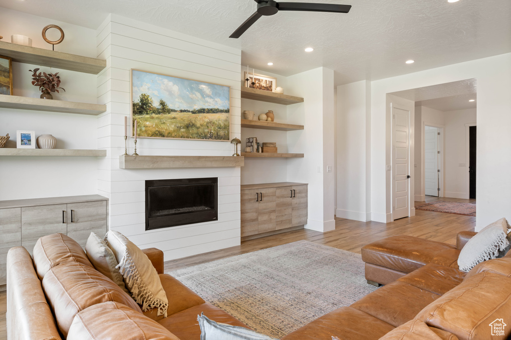 Living area with wood finished floors, a ceiling fan, baseboards, recessed lighting, and a large fireplace