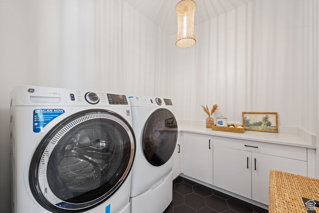 Laundry room featuring separate washer and dryer, dark tile patterned floors, and cabinet space