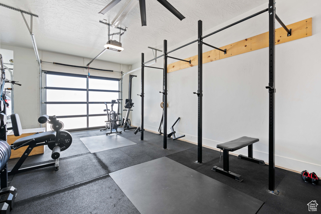 Workout room with a textured ceiling, a garage, and baseboards
