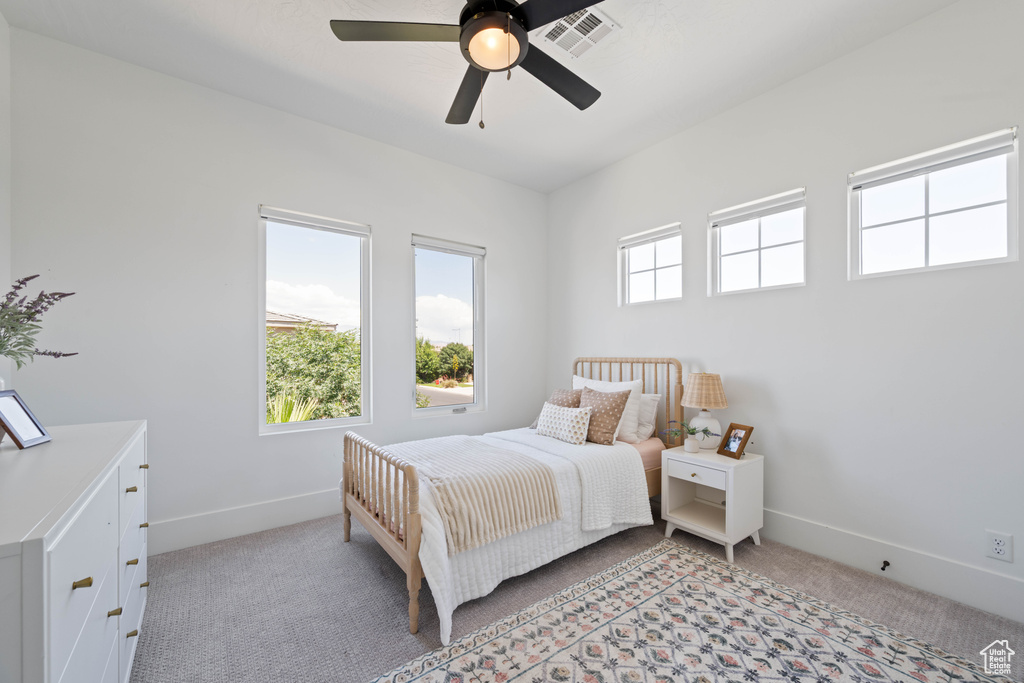Bedroom with light colored carpet, baseboards, and a ceiling fan