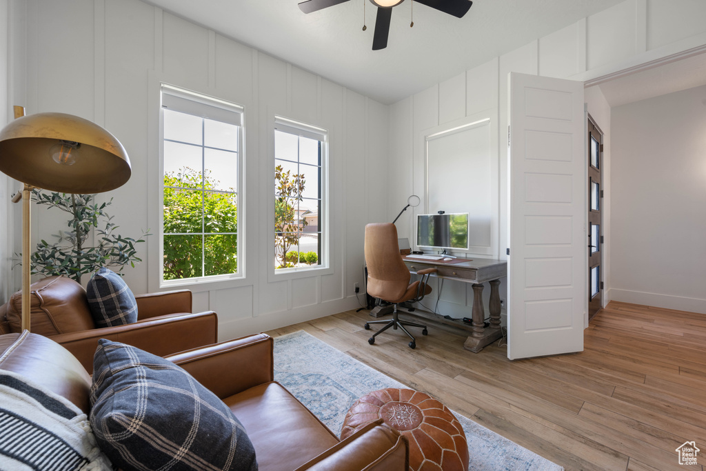Office area featuring ceiling fan, a decorative wall, light wood-style flooring, and baseboards