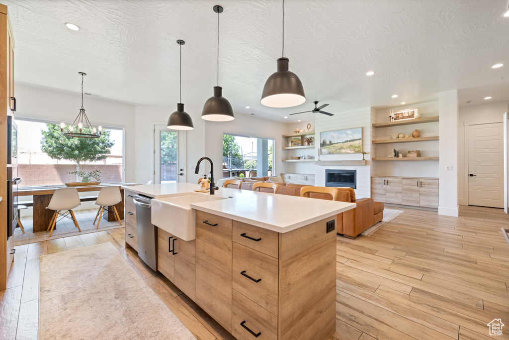 Kitchen with stainless steel dishwasher, a sink, an island with sink, recessed lighting, and light wood-style floors
