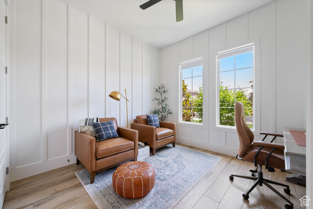 Office with a decorative wall, light wood-type flooring, and ceiling fan
