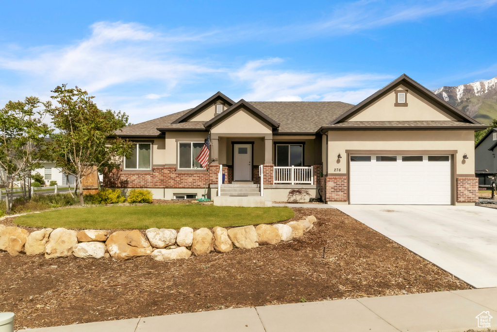 Craftsman house with brick siding, stucco siding, a front lawn, a garage, and concrete driveway