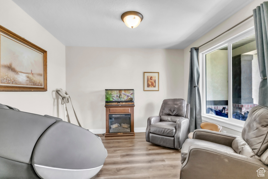 Living area with light wood finished floors, a glass covered fireplace, and baseboards