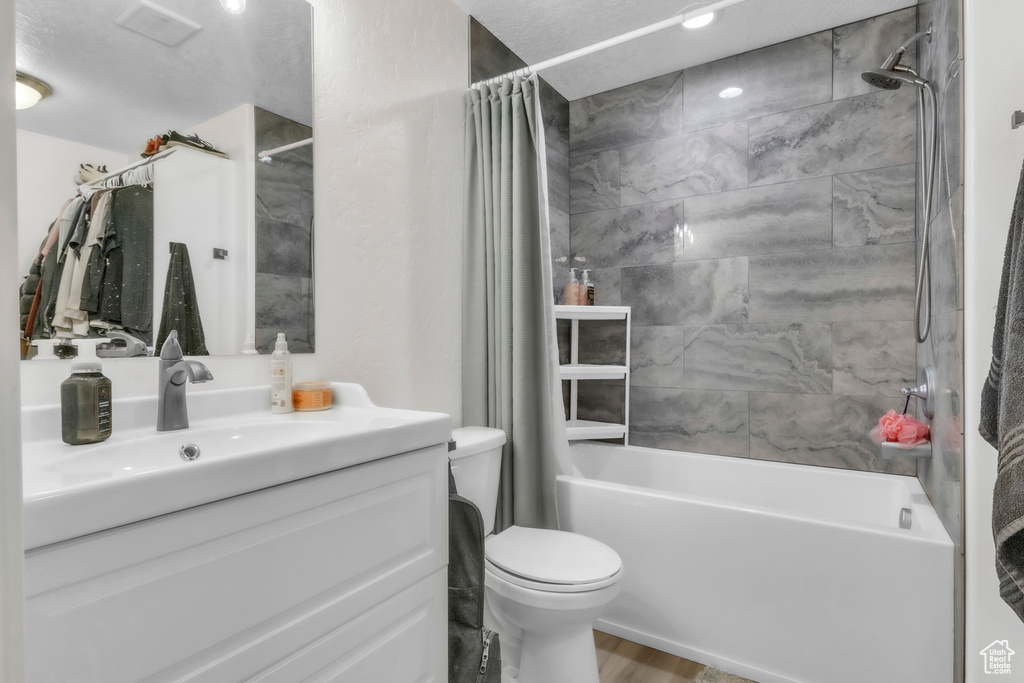 Full bath featuring shower / bath combination with curtain, vanity, toilet, and wood finished floors