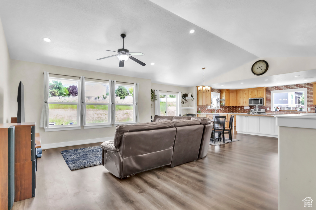 Living area with a ceiling fan, recessed lighting, vaulted ceiling, wood finished floors, and a chandelier