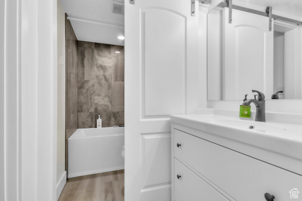 Full bathroom with vanity, wood finished floors, and shower / tub combination