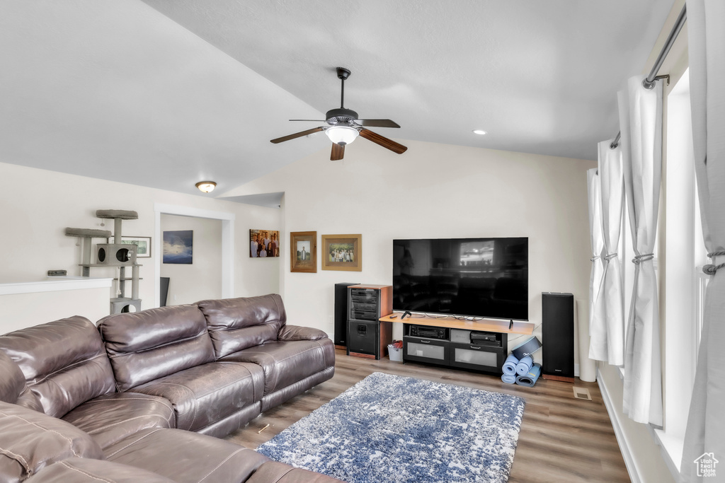 Living room with wood finished floors, a ceiling fan, and vaulted ceiling