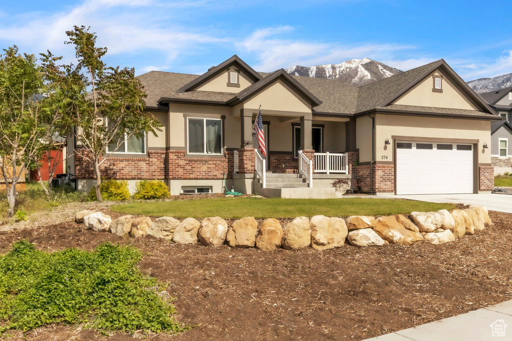 View of front of house featuring covered porch, brick siding, stucco siding, driveway, and a front yard