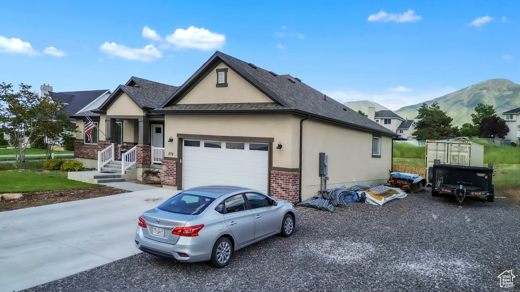 View of front of property with stucco siding, a mountain view, concrete driveway, brick siding, and an attached garage