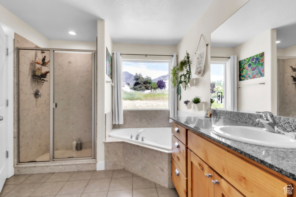 Full bathroom featuring vanity, a shower stall, a garden tub, and tile patterned floors