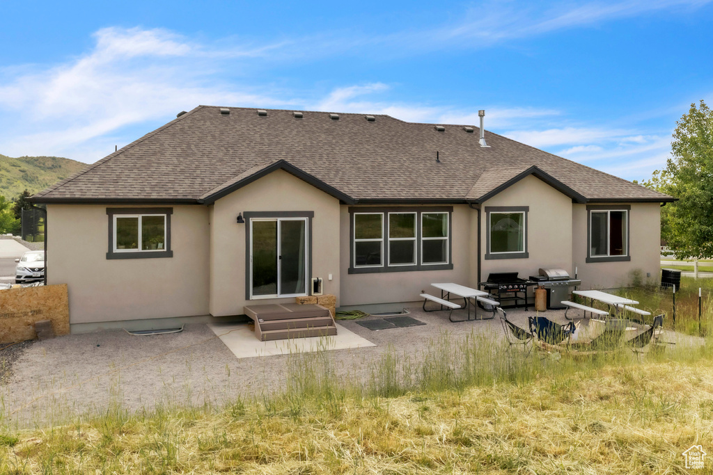 Rear view of house with a patio area, a shingled roof, and stucco siding
