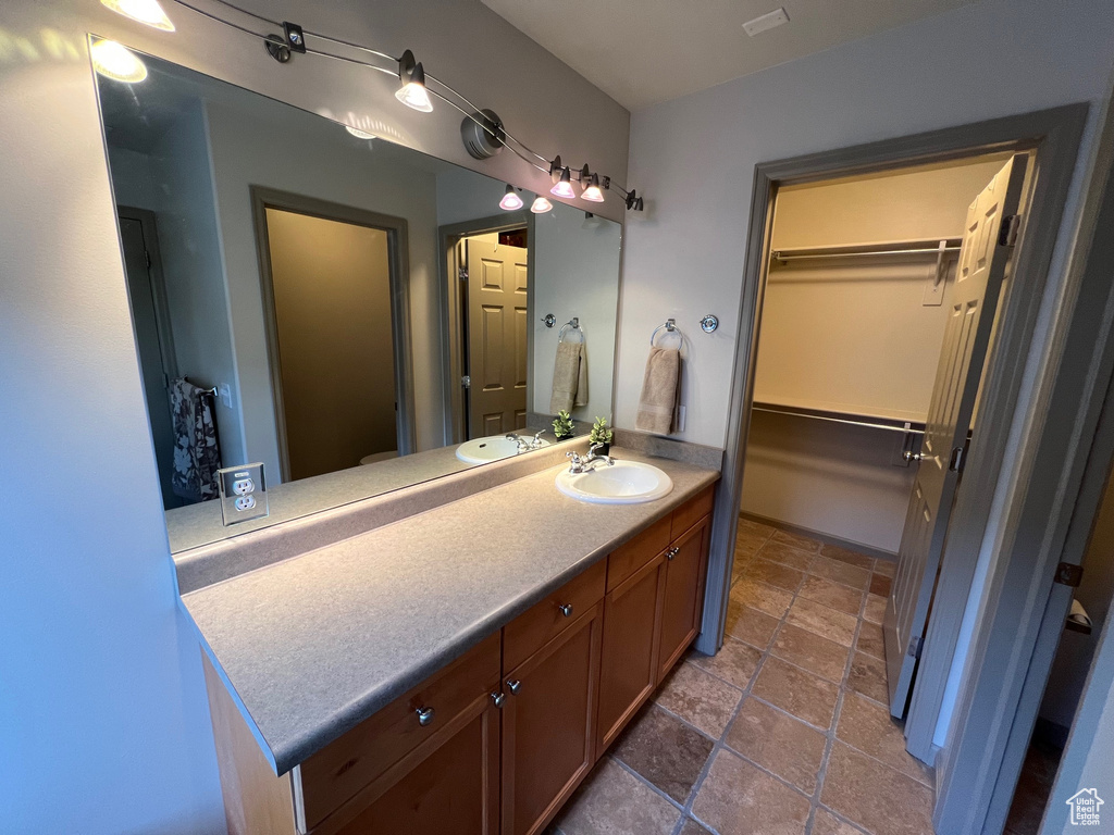 Bathroom featuring vanity, stone finish floors, and a walk in closet
