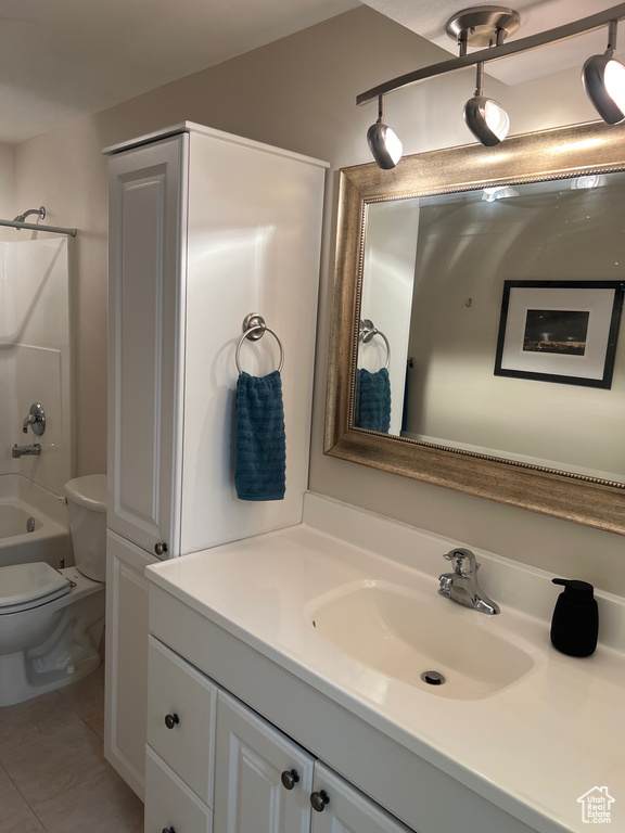 Bathroom with vanity, toilet, tile patterned floors, and washtub / shower combination
